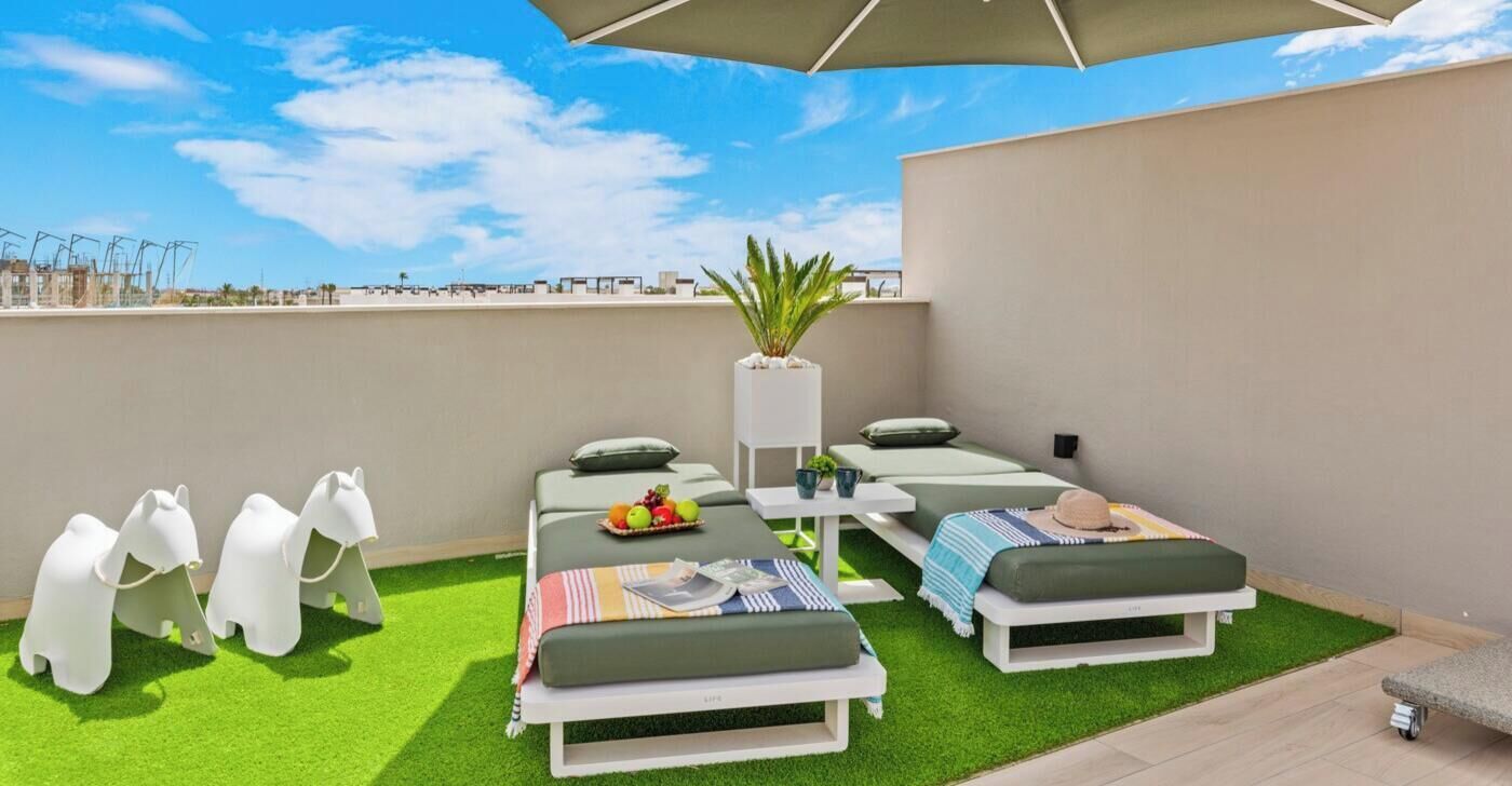 Une terrasse sur le toit avec deux chaises longues, une petite table agrémentée d’une plante et des figurines décoratives d’éléphants.