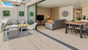 A modern living space with a sofa, dining table, chairs, a TV, and decorative plants. - Apartment 'Penthouse Santa Rosalia' with Private Pool, Wi-Fi and Air Conditioning (Santa Rosalia Torre Pacheco)