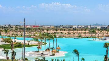A resort with a large pool, palm trees, and a view of the city in the background.