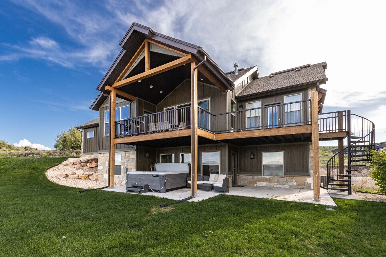 A two-story house with a balcony, stone foundation, and a stone retaining wall.