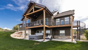 A two-story house with a balcony, stone foundation, and a stone retaining wall. - Private Beach Access! Tennis/Pickleball Courts Nearby! Game Room! (Fish Haven)