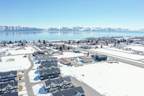 A residential area with houses, a road, and a body of water with mountains in the background. - Lakeside Getaway - Sleeps 16 (Garden City)