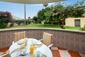 A round table with a white tablecloth, chairs with striped cushions, and a tiled wall with a geometric pattern.