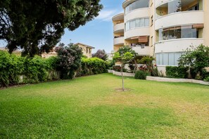A residential building with multiple balconies, a well-maintained lawn, and surrounding greenery.
