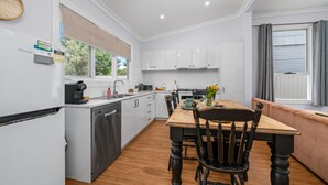 Een moderne keuken met witte kastjes, een houten eettafel en een zwarte stoel.