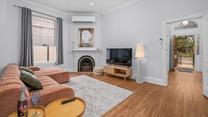 Een moderne woonkamer met een bank, televisie, open haard en een houten vloer.