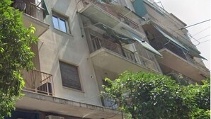 Edifício com vários andares, varandas, aparelhos de ar condicionado e uma vitrine com roupas à mostra.
