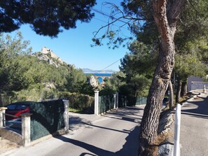 Un chemin pavé mène à un bâtiment d’où l’on peut admirer un pont et des montagnes.
