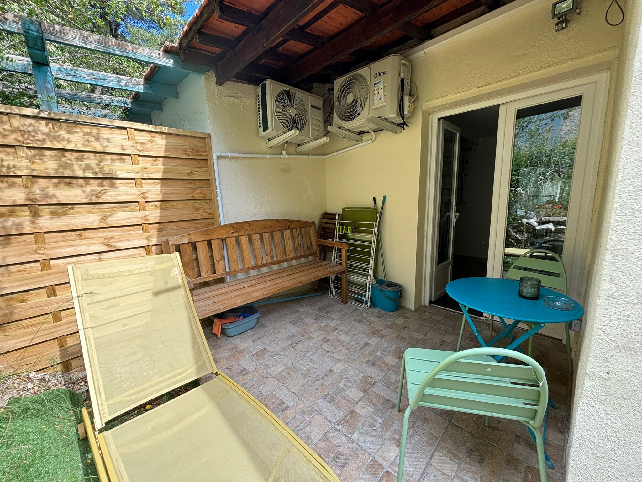Un patio con una panchina di legno, un tavolo e sedie.