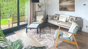 A modern living room with a sofa, armchair, coffee table, and a view of greenery through a sliding door. - 2 bedroom beautiful home in Lemmer (Lemmer)