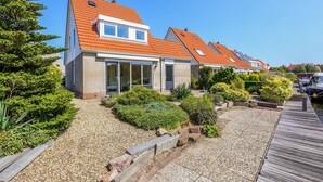 A row of modern houses with orange roofs, large windows, and a well-maintained garden.