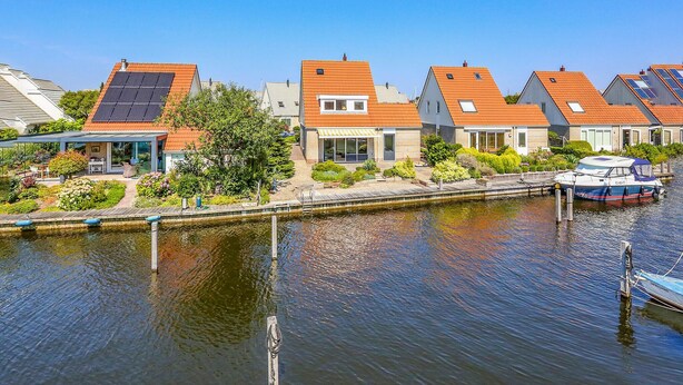 A canal-side residential area with houses featuring sloped roofs and solar panels.