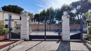 Ein verschlossenes Tor mit einem gepflasterten Weg, der zu einem Gebäude führt, an dem ein Schild mit der Aufschrift 'ATLANTIS' angebracht ist.