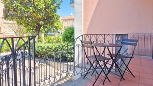 Ein Balkon mit schmiedeeisernem Geländer, einem kleinen Tisch und zwei Stühlen.