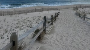 Una spiaggia con una recinzione in legno e una vista aperta sull'oceano.