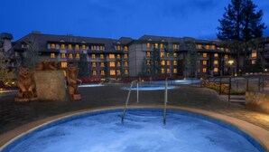 Un hôtel doté d’une grande piscine extérieure, de statues de lions en pierre et d’un immeuble à plusieurs étages dont les fenêtres sont illuminées.