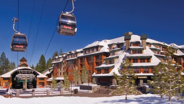 Une station de ski dotée d’un réseau de téléphériques, d’un grand bâtiment avec de nombreux balcons et d’un paysage enneigé.
