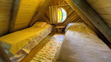 Een gezellige slaapkamer onder de dakpannen met twee bedden, een tafeltje en een raam dat voor natuurlijk licht zorgt.