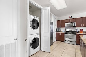Una cocina moderna con electrodomésticos blancos, horno doble y microondas.