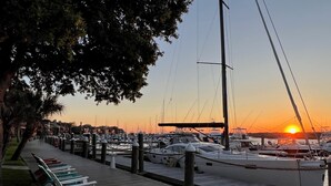 Un port de plaisance avec des bateaux amarrés, une passerelle en bois et un coucher de soleil en arrière-plan.