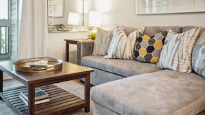 Un salon avec un canapé gris, une table basse en bois et un plateau contenant des livres.
