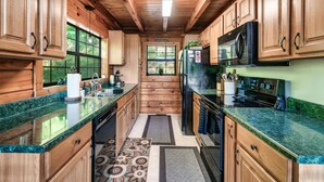 Una cocina con armarios de madera, encimeras de granito, estufa y refrigerador.