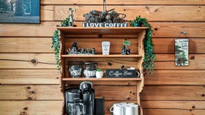Una estantería de madera con una cafetera, tazas y un letrero que dice 'Coffee Bar'.