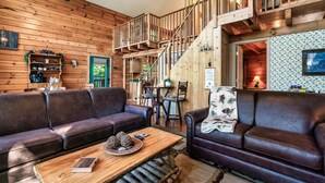Un interior acogedor de madera con una escalera, sofás de cuero y una estación de café.