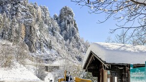 Un paysage montagneux enneigé avec un bâtiment en bois et un véhicule jaune.