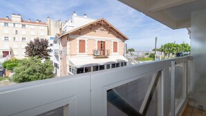 Un balcon d’où l’on peut voir un immeuble abritant un restaurant appelé « KRAKEN », ainsi qu’une enseigne indiquant les heures d’ouverture du restaurant.