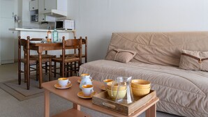 Un salon confortable avec un canapé, une table à manger et des chaises, ainsi qu’un coin cuisine équipé d’un four à micro-ondes et de placards.