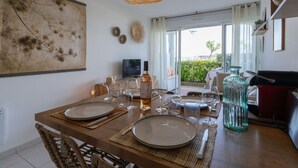 Un comedor con una mesa de madera preparada para cuatro personas, un cuadro abstracto grande y vistas al exterior.