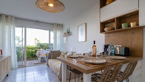 Un comedor con una mesa de madera, sillas de mimbre y una lámpara colgante.