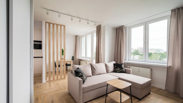Una sala de estar moderna con un sofá modular, una mesita y vistas de la ciudad a través de amplios ventanales.