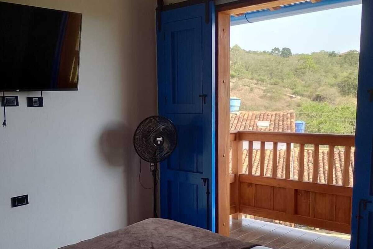 A bedroom with a bed, a fan, and a TV.