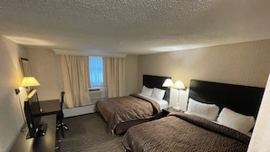 A hotel room with two beds, a desk, a chair, a lamp, and a window with curtains. - ALMAC HOTEL Lac La Biche (Lac La Biche)