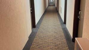 A hotel hallway with a skylight, carpeted floor, and doors on both sides. - ALMAC HOTEL Lac La Biche (Lac La Biche)