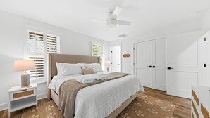 A bedroom with a bed, nightstand, and a ceiling fan.