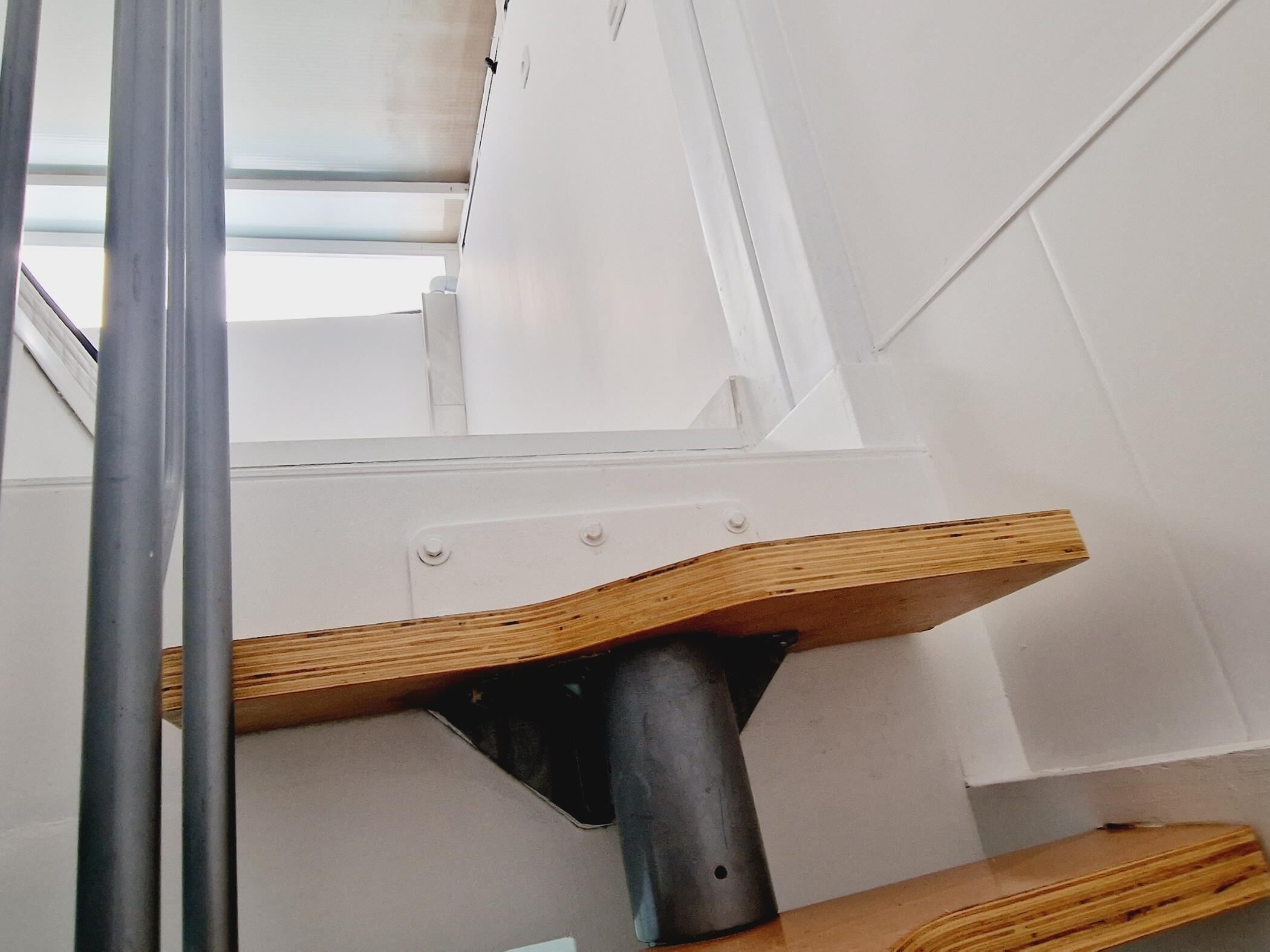 A staircase with a wooden handrail and metal support structure.