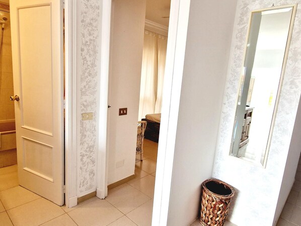 A hallway with a white door, a wicker basket, and a mirror on the wall.