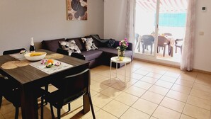 Un salon moderne comprenant une table à manger, un canapé et donnant sur un espace extérieur grâce à une porte-fenêtre coulissante.