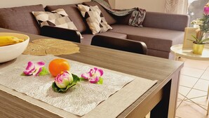 Une table à manger avec un set de table, un saladier de fruits et des fleurs décoratives.