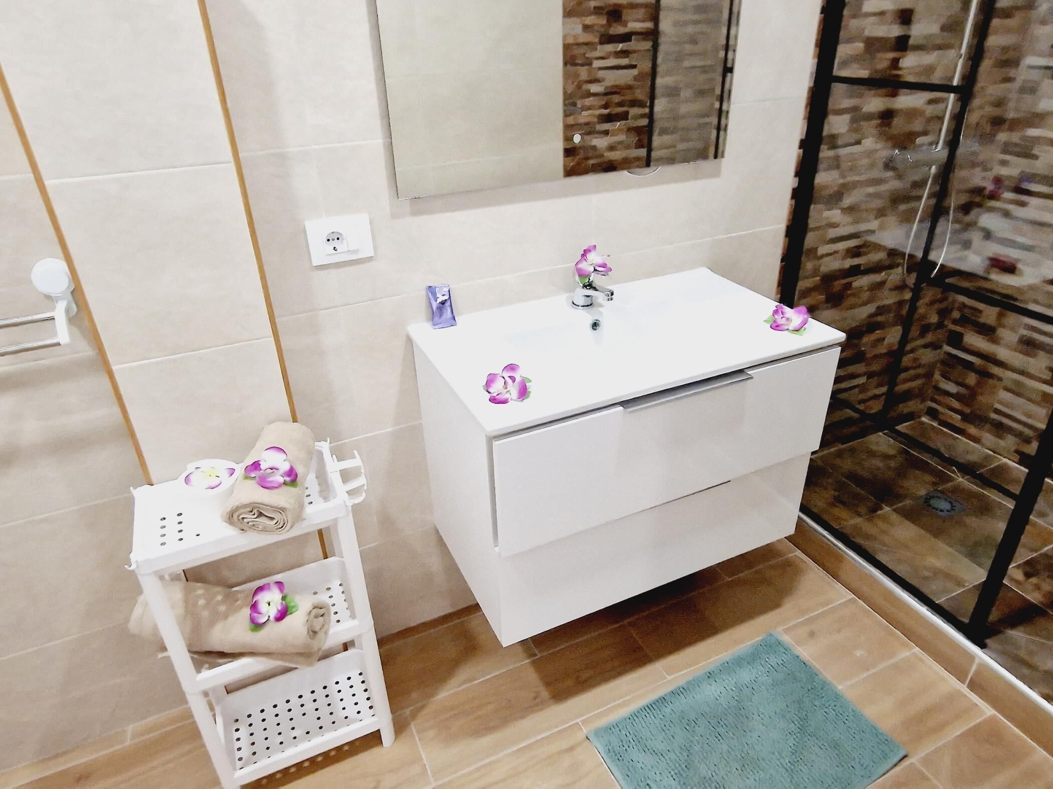 A bathroom with a white sink, a mirror, and a shower area.