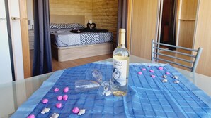 Een kamer met een bed, een tafel met een fles wijn en een blauwe tafelkleed.