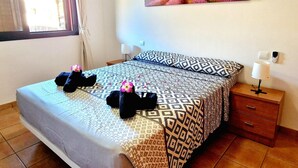 A hotel room with a bed, a nightstand, a lamp, and a painting on the wall. - Paraiso, 2 Bedroom, Terrace, wifi free (Playa Paraíso)