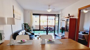 A modern kitchen with a wooden countertop, white cabinets, and a dining area with a table and chairs. - Paraiso, 2 Bedroom, Terrace, wifi free (Playa Paraíso)