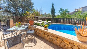 Une terrasse extérieure avec un mur en pierre, une piscine et des chaises longues.