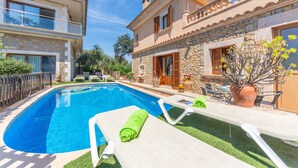 Une piscine avec des chaises longues et un bâtiment en pierre doté d’un balcon.