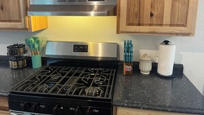Une cuisine dotée de meubles en bois, d’une hotte en acier inoxydable, d’une cuisinière à gaz et de divers ustensiles et appareils de cuisine.