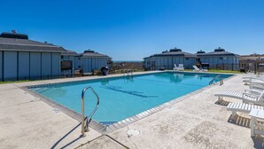 Une piscine avec des chaises longues et un ciel bleu azur.